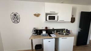 Cocina compacta con microondas, cafetera y refrigerador pequeño.