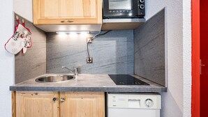 A compact kitchen with a built-in microwave, a stainless steel sink, and a dishwasher.