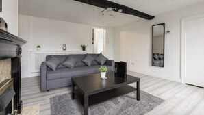 Ein modernes Wohnzimmer mit grauem Sofa, einem dunklen Couchtisch und einem Kamin.