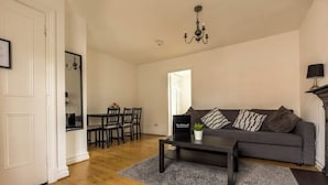 A living room with a grey sofa, a coffee table, and a chandelier. - The Old Sawmill - Entire apartment - Syston (Leicestershire)