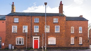 A two-story brick building with a red door and multiple windows. - The Old Sawmill - Entire apartment - Syston (Leicestershire)