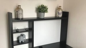 A black console table with shelves and a central white panel, decorated with a potted plant and two glass bottles. - The Old Sawmill - Entire apartment - Syston (Leicestershire)
