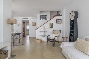Amplia sala de estar con sofá, una silla, una mesa de comedor y una escalera.