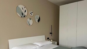 Une chambre à coucher comprenant un lit, des tables de chevet, une armoire et des miroirs fixés au mur.