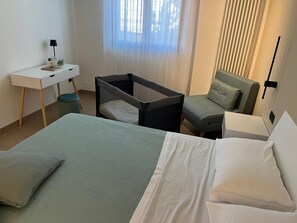A bedroom with a bed, a desk, a chair, a small table, a window with curtains, and a sofa. - Vacation 103, the perfect vacation home, close to the station (Monopoli)