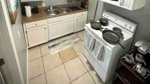 A kitchen with white cabinets, a stove, and a microwave.