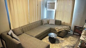 A living room with a sectional sofa, a round coffee table, and a patterned rug.