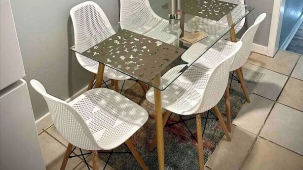 A dining area with a glass table and white chairs.