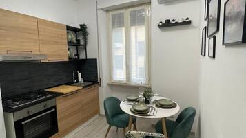 A modern kitchen with a dining area, featuring a stove, oven, and wooden cabinets.