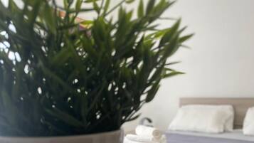 A potted plant in the foreground with a bed in the background.