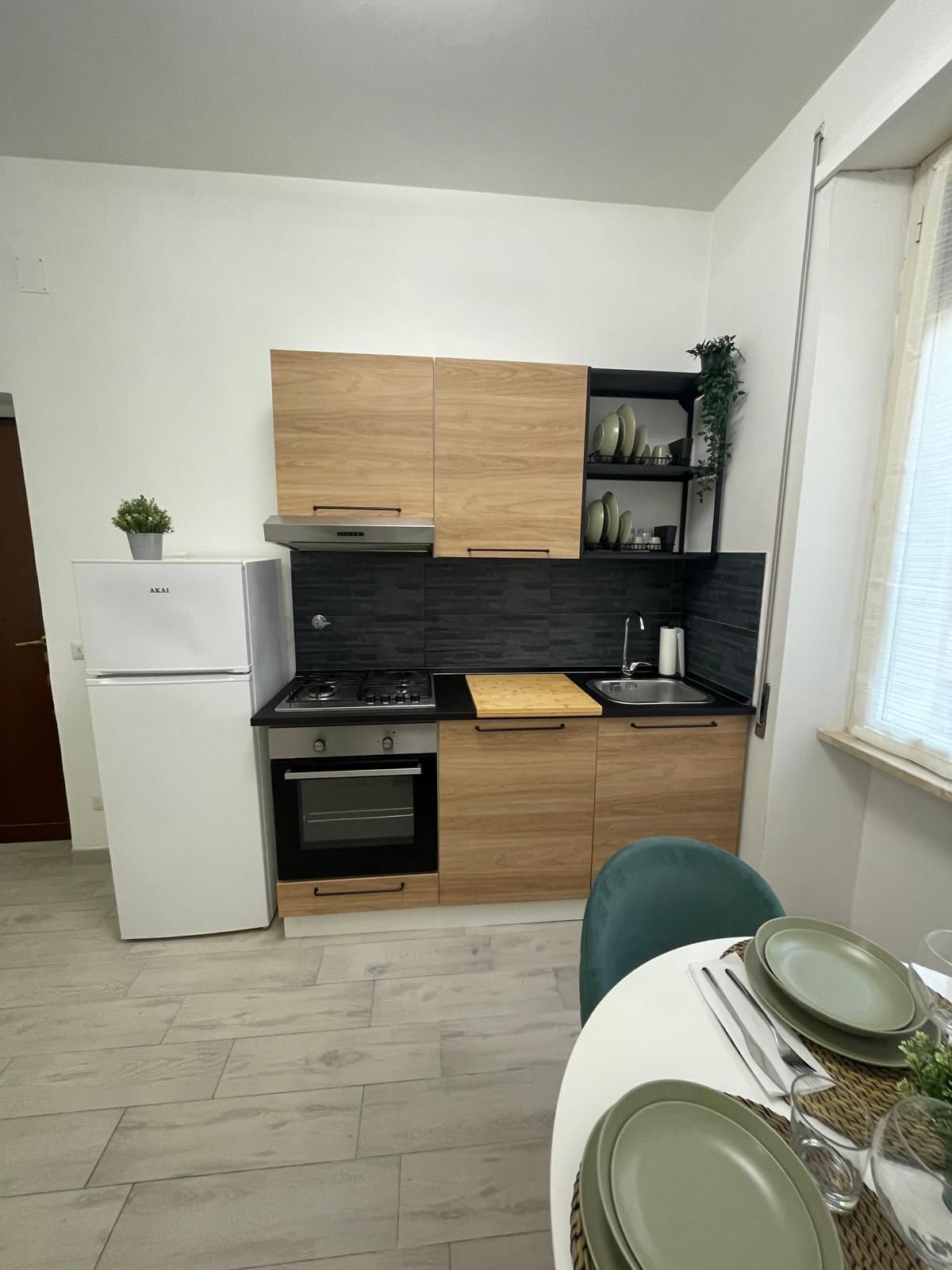 A compact kitchen with wooden cabinets, a white refrigerator, a stove, and a sink.