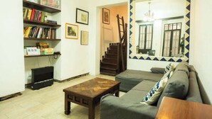 A living room with a sofa, a coffee table, a bookshelf, and a staircase. - Regina 70 · Amazing Historic Colonial Duplex by Cathedral (Mexico City)