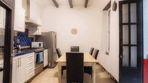 A compact kitchen with white cabinets, a microwave, a stove, and a dining table with chairs. - Regina 70 · Amazing Historic Colonial Duplex by Cathedral (Mexico City)