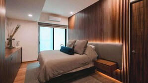 A modern bedroom with a bed, bedside table, and a window. - Rooftop Pool Oasis in Roma Norte w/ Gym & A/C (Mexico City)