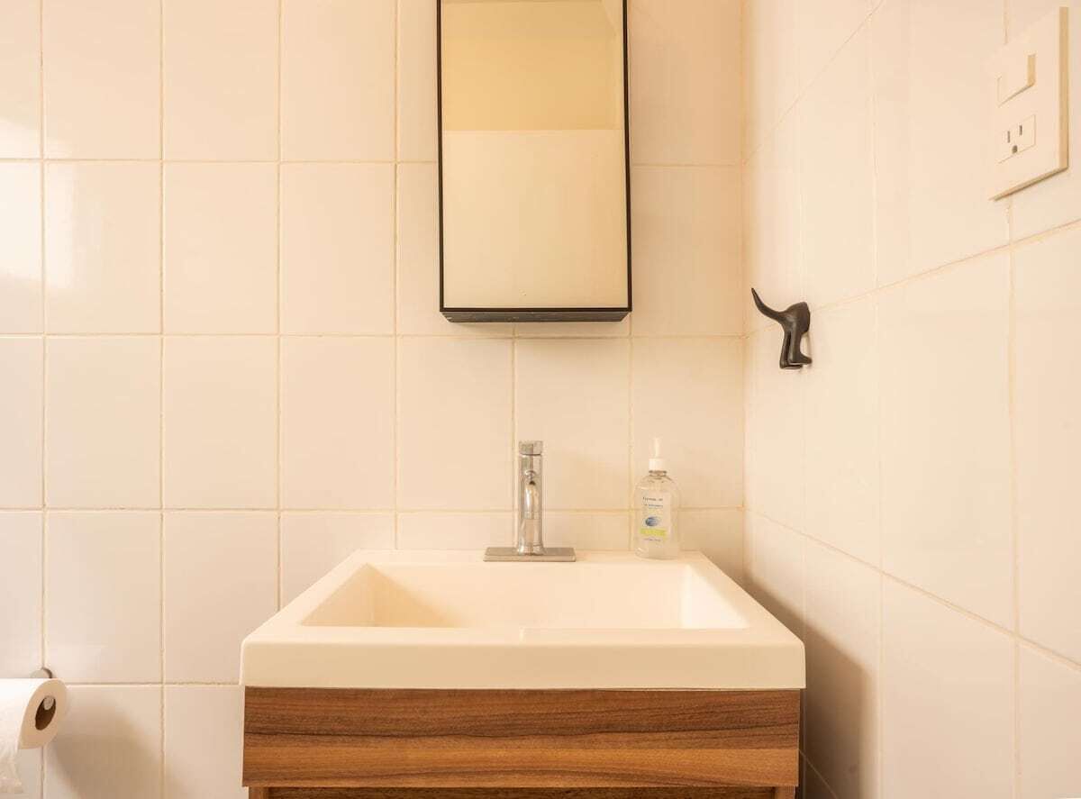 A bathroom with a white sink, a mirror, and a toilet paper roll.