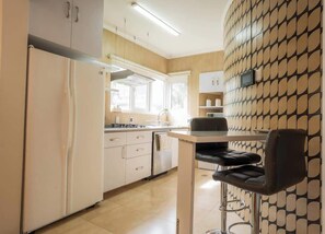 Een moderne keuken met een koelkast, fornuis en barkrukken.