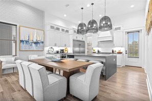 Una cocina moderna con armarios blancos, una isla central e iluminación colgante.