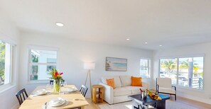 A bright, spacious living room with a dining area, large windows, and a view of the beach. - Beach Condo King Bed Lush Patio w BBQ Birch Key Four (Fort Lauderdale)