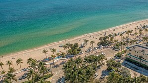 An aerial view of a beach with palm trees, a parking lot, and a building with a flat roof. - Beach Condo King Bed Lush Patio w BBQ Birch Key Four (Fort Lauderdale)