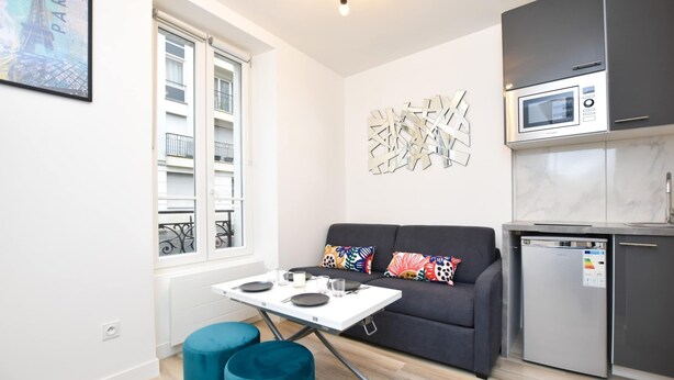 A compact living space with a kitchenette, a dining table, and a sofa.