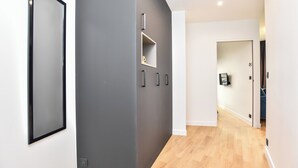 A modern hallway with a grey accent wall, a framed picture, and a small shelf with a decorative item. - Chic Apartment - 1br/4p - Near Opera Garnier (Paris)