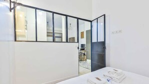 A hotel room with a large mirror, a bed with neatly folded towels, and a view of the adjacent room through the mirror. - Bright Apartment - 1br/4p - Bibliotheque Francois Mitterrand (Paris)
