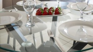 A dining table set with plates, glasses, and a plate of strawberries.
