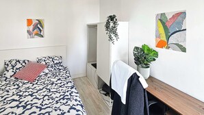 A bedroom with a bed, a desk, a chair, a plant, and artwork on the walls. - Private Room in a Shared Flat - Villeurbanne (Villeurbanne)