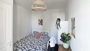 A bedroom with a bed, a hanging light fixture, a potted plant, and wall art. - Private Room in a Shared Flat - Villeurbanne (Villeurbanne)