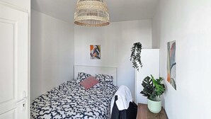 A bedroom with a bed, a hanging plant, and two wall art pieces. - Private Room in a Shared Flat - Villeurbanne (Villeurbanne)