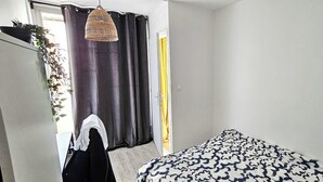 A bedroom with a bed, a hanging light fixture, a door, and a window with curtains. - Private Room in a Shared Flat - Villeurbanne (Villeurbanne)