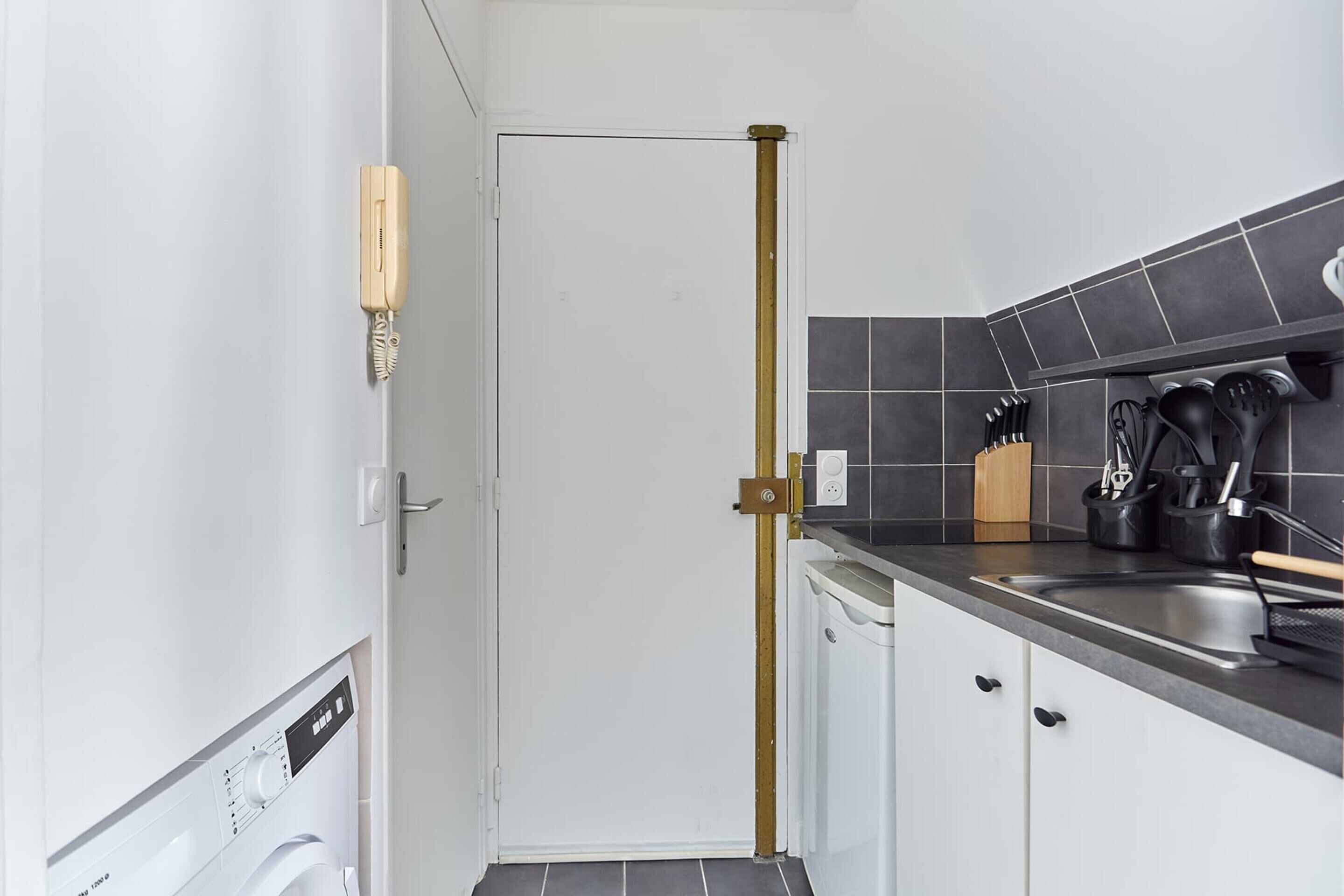 Cocina compacta con lavavajillas, un lavabo y una encimera con utensilios de cocina.