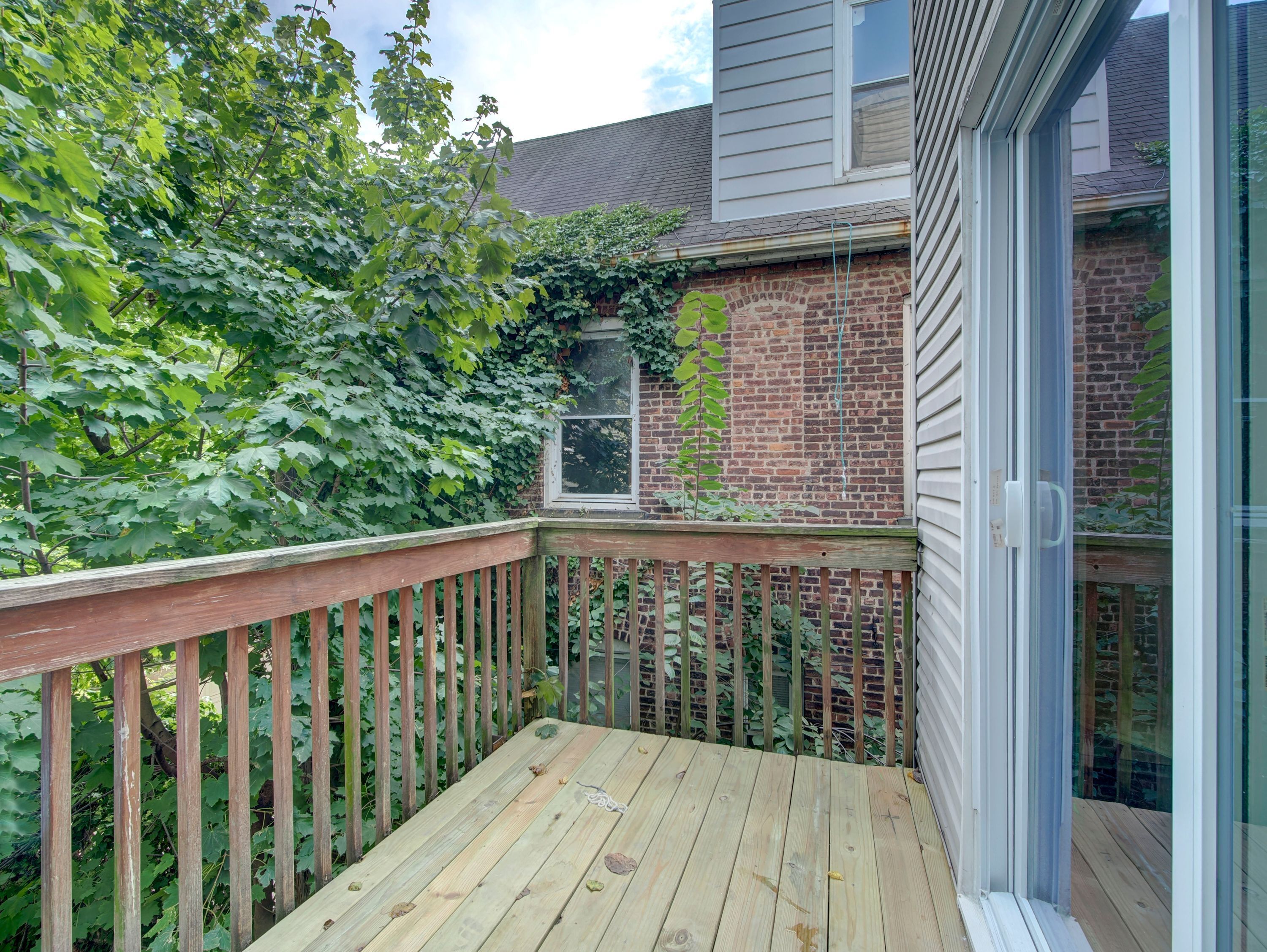 A wooden deck with a brick wall and a window.