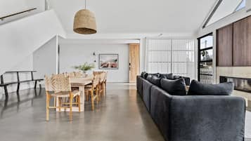 A modern interior with a dining area, a sofa, and a hanging light fixture.