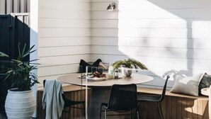 Ruokailutilassa on pyöreä pöytä, mustat tuolit ja kattotuuletin. Vasemmalla puolella on ikkuna, josta tulee luonnonvaloa, ja ruukussa oleva kasvi.