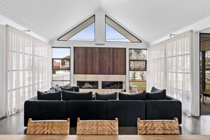 A modern living room with a sectional sofa, a fireplace, and large windows. - Maple on Albert Berry - by Linnaeus Collection (Berry)