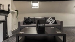 A modern living room with a sofa, a coffee table, and a fireplace. - Entire apartment - Syston The Carpenters Loft (Leicestershire)