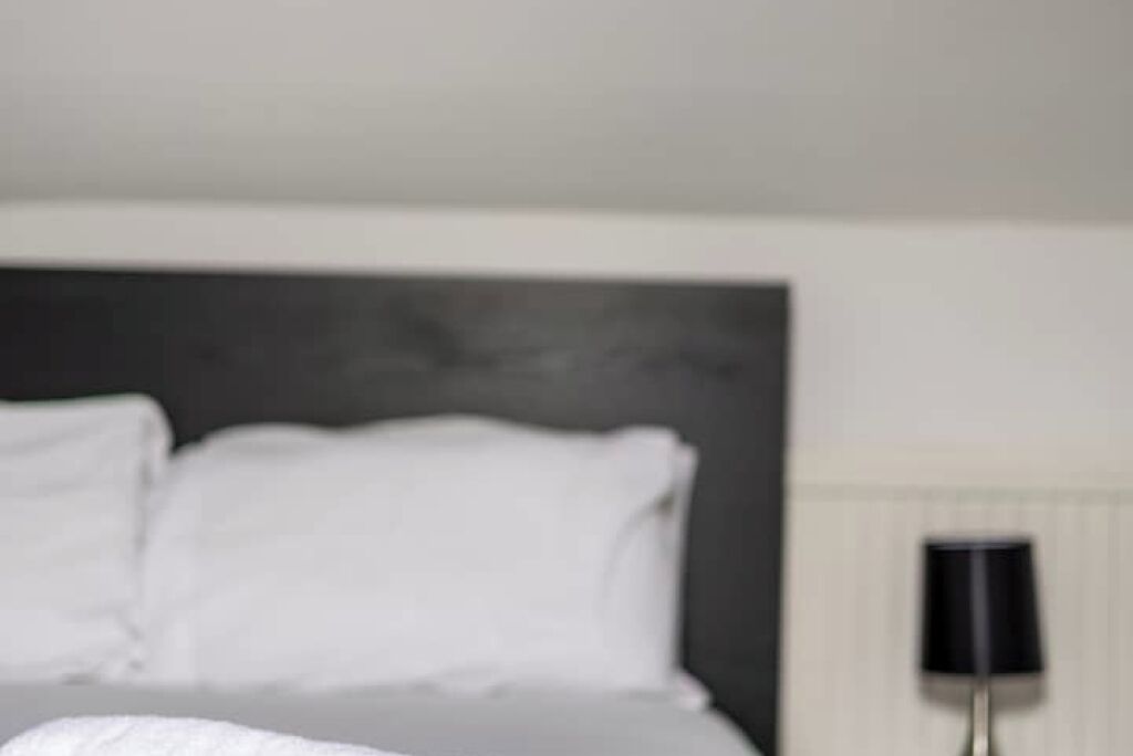 Una habitación de hotel con una cama grande, una mesita de noche y una lámpara.