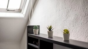 A corner of a room with a dark wooden shelf holding three potted plants against a textured wall. - Entire apartment - Syston The Carpenters Loft (Leicestershire)