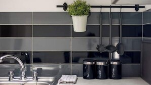 A kitchen with a stainless steel sink, a potted plant, and three containers labeled "Tea," "Sugar," and "Coffee." - Entire apartment - Syston The Carpenters Loft (Leicestershire)