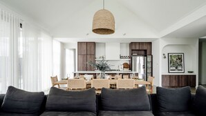 A modern living room with a dark grey sofa, a dining area with a wooden table and chairs, and a kitchen in the background. - Maple on Edward Berry - by Linnaeus Collection (Berry)