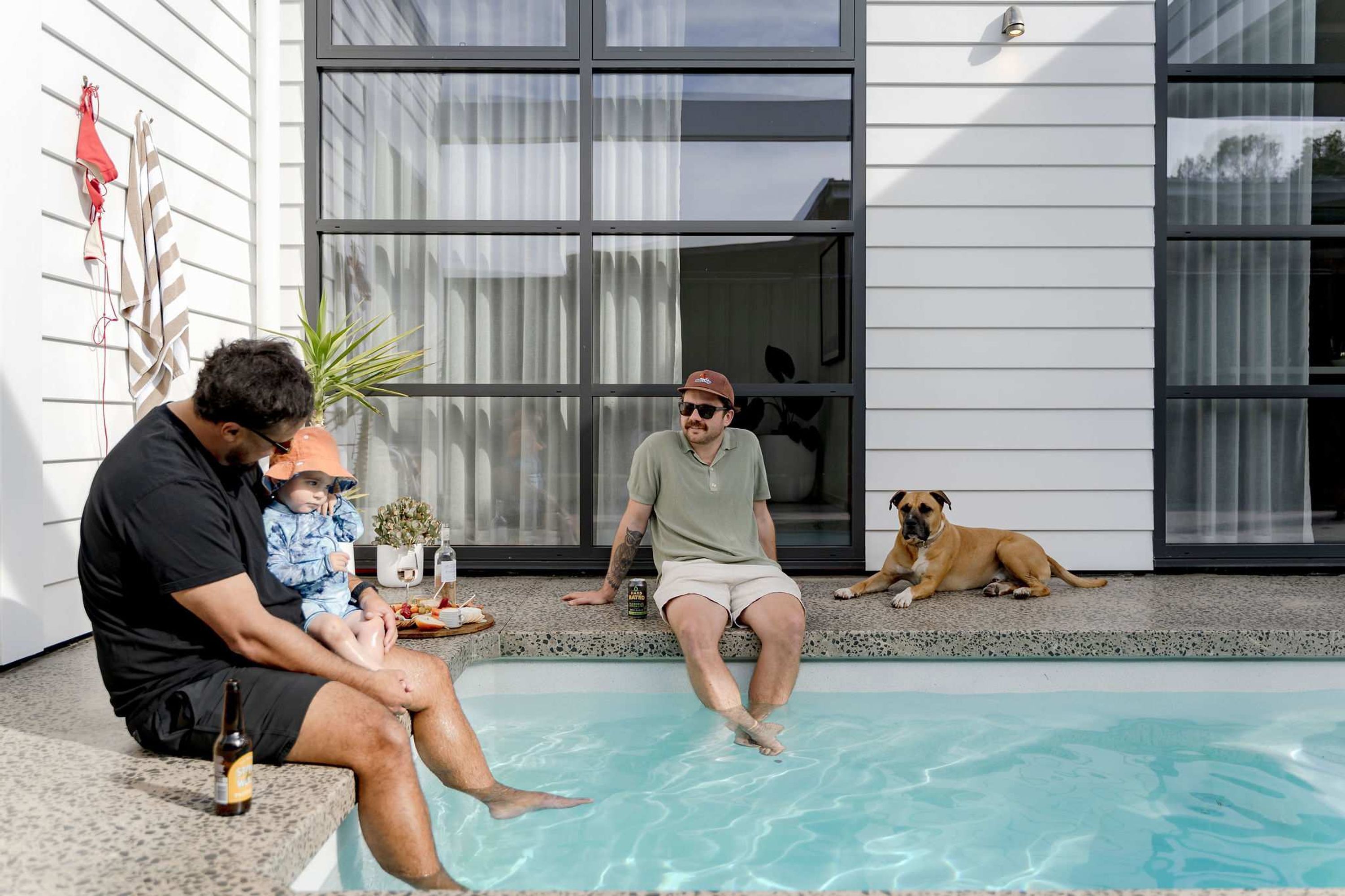 A poolside scene with a man, a child, and a dog.