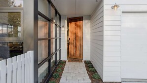 A modern house entrance with a wooden door, a white picket fence, and a stone pathway leading to the door. - Maple on Edward Berry - by Linnaeus Collection (Berry)