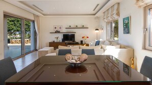 Una sala de estar moderna con una mesa de comedor de vidrio, un conjunto de sofá, un televisor y un cuenco decorativo.
