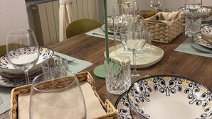 A dining table set with plates, glasses, and cutlery, with a lamp and baskets on the table. - Cappuccini's B&B (Livorno)