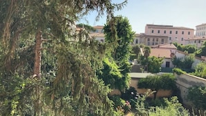 A view of a building with a red-tiled roof, surrounded by greenery and other buildings. - Cappuccini's B&B (Livorno)