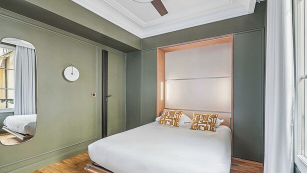 Un dormitorio moderno con una cama grande, un espejo y un ventilador de techo.