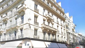 Un edificio de varios pisos con arquitectura clásica, que cuenta con balcones y ventanas grandes.