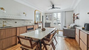 Una cocina moderna con armarios de madera, encimera de mármol y un comedor con sillas de mimbre.