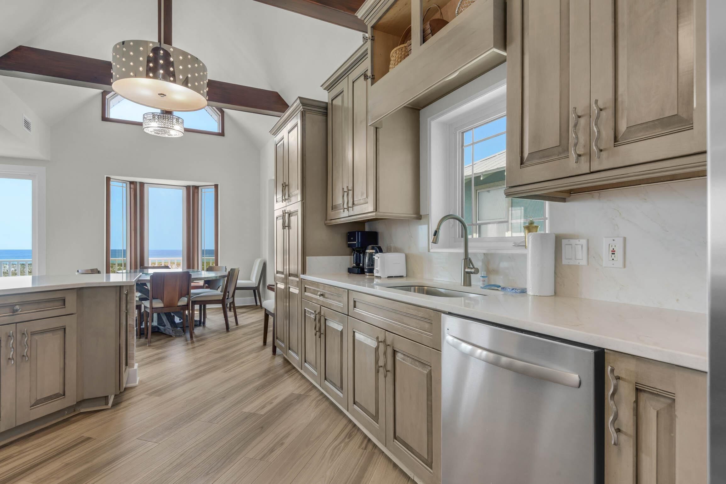 A modern kitchen with a large island, stainless steel appliances, and a view of the ocean.
